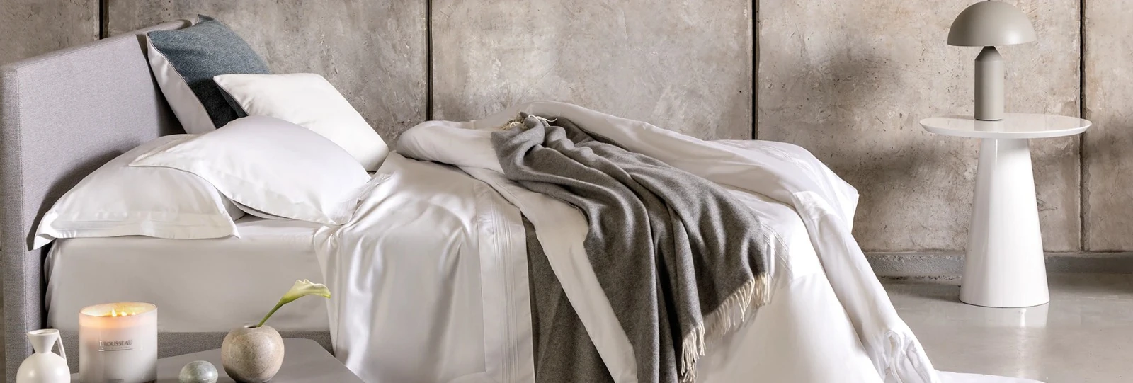 Cama com roupa de cama branca e manta cinza Trousseau